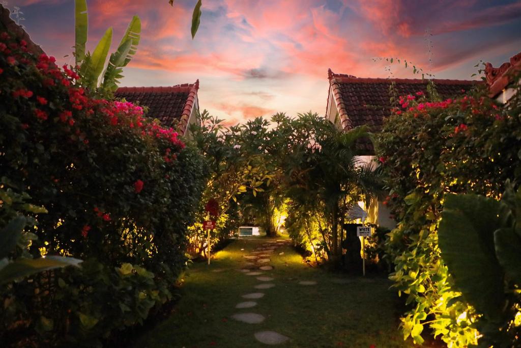 a garden with flowers and an arch with a building at Bingin Bienvenue Guest House in Uluwatu