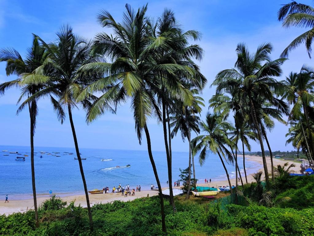 a beach with palm trees in front of the ocean at Colva beach Xaviers Guest House in Colva