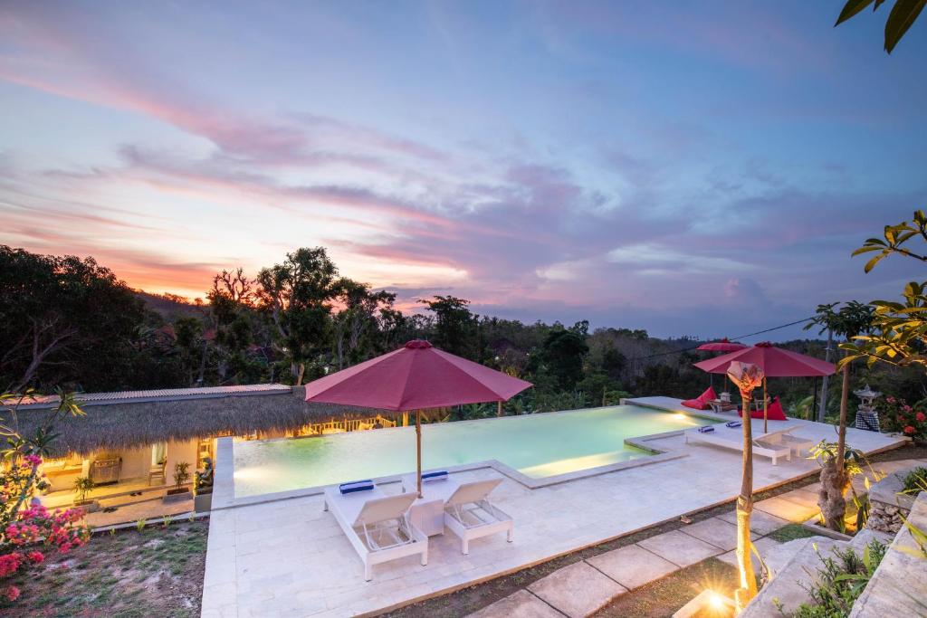 uma imagem de uma piscina com guarda-sóis em Wijaya Cottage Nusa Penida em Nusa Penida