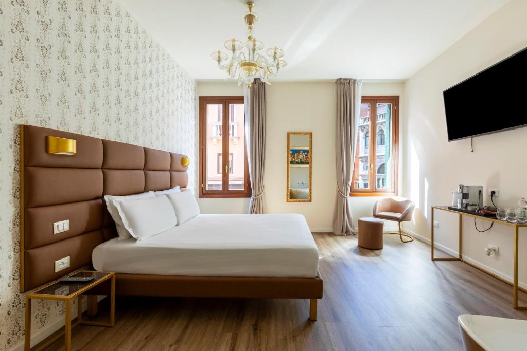 a hotel room with a bed and a tv at Numa Venice Palazzo Orseolo in Venice