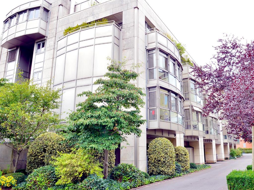 un edificio blanco con un árbol delante en Residence Zug, en Zug