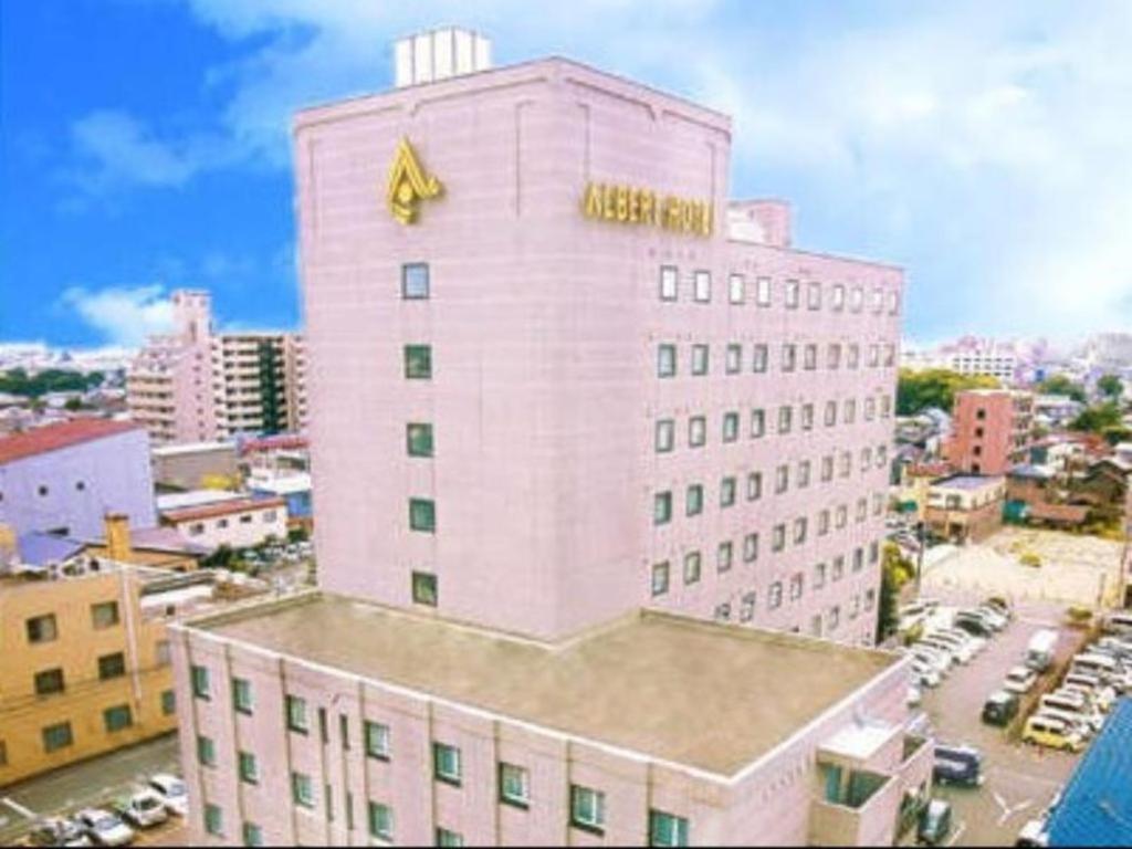 a large pink building with a yellow sign on it at Albert Hotel in Akita