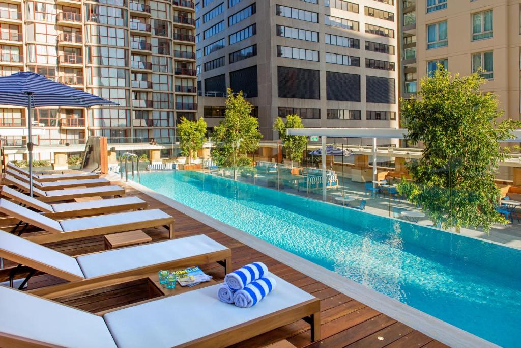 una piscina all'aperto con sedie a sdraio accanto a un edificio di Kimpton Margot Sydney, an IHG Hotel a Sydney