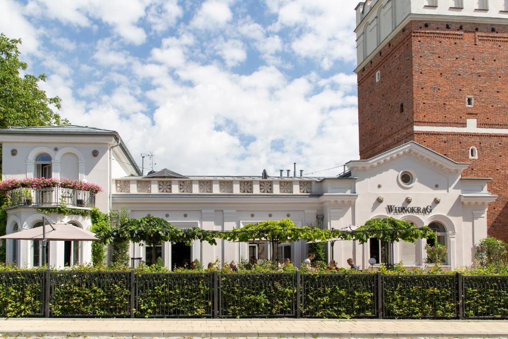 un grand bâtiment blanc avec une tour en briques dans l'établissement Pokoje Gościnne WIDNOKRĄG, à Sandomierz