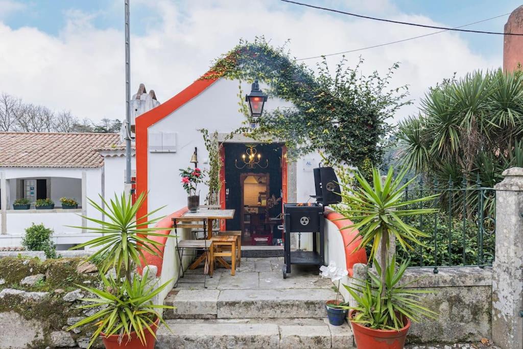 une maison avec une terrasse couverte dotée d'une table et de plantes dans l'établissement Unique Luxurious 17-Century Smart Chapel in Center, à Sintra