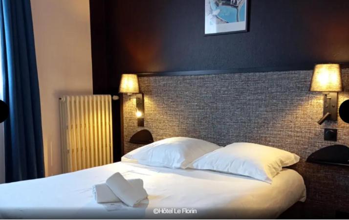 a bedroom with a bed with white sheets and pillows at Hôtel Le Florin in Rennes