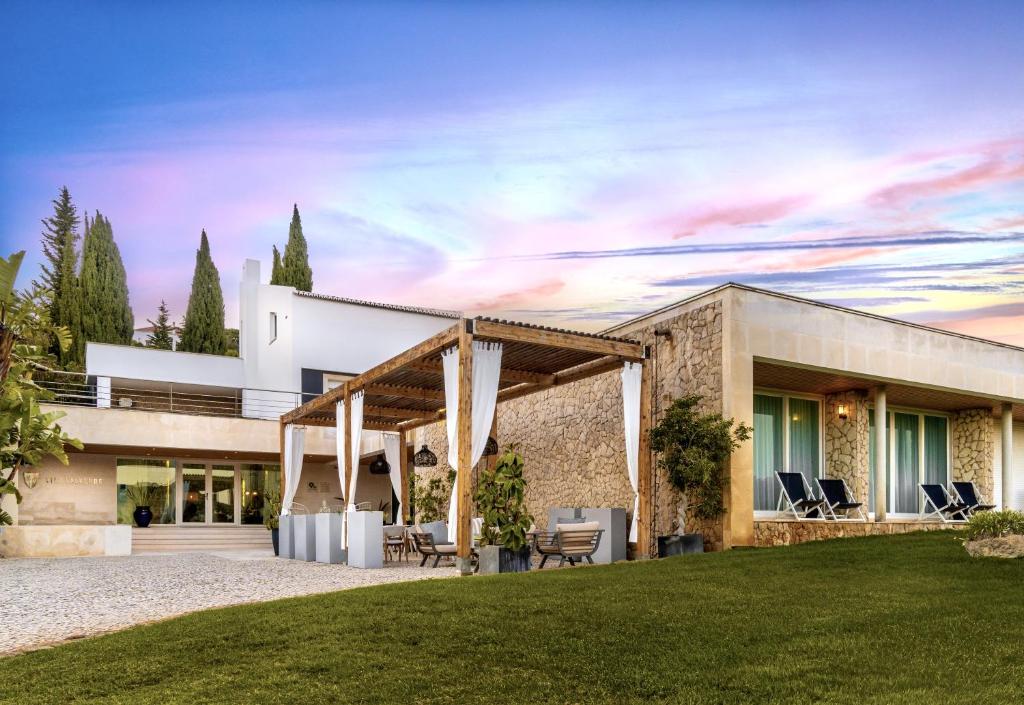 uma casa com uma fachada de pedra com um relvado em Vila Valverde Design Country Hotel na Praia da Luz