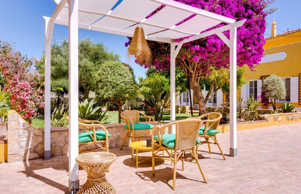 a white pergola with chairs and tables on a patio at Quinta Almargem Lusitano - Farm House in Tavira