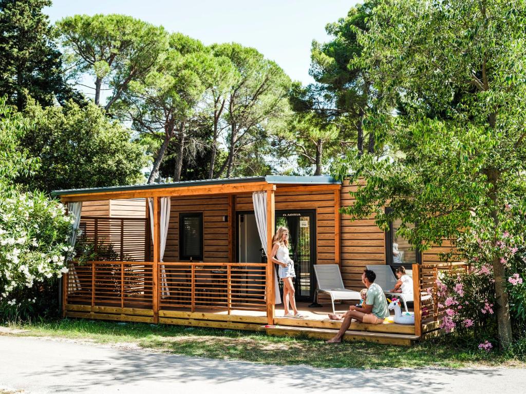 una cabaña en el bosque con gente sentada en el porche en Zaton Holiday Resort Mobile Homes, en Nin