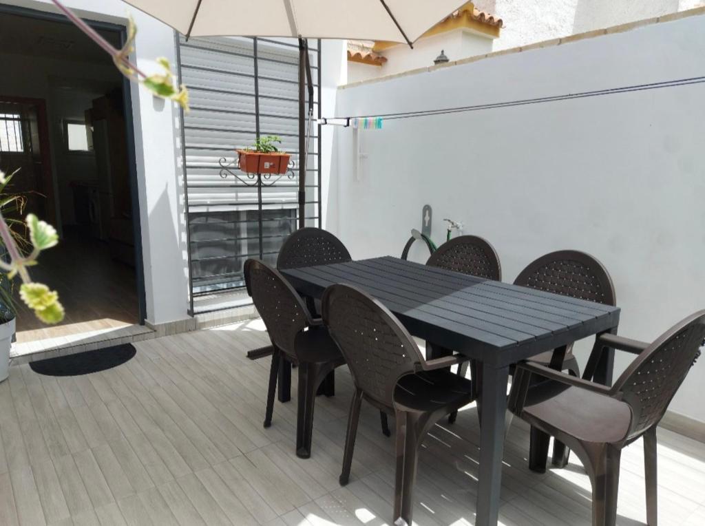 - une table à manger avec des chaises et un parasol dans l'établissement Estudio Caño Guerrero Matalascañas, à Matalascañas