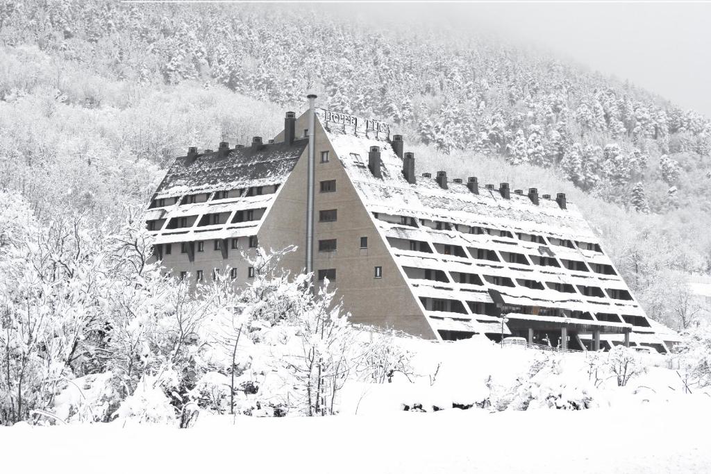 um grande edifício na neve com uma montanha em RVHotels Tuca em Vielha