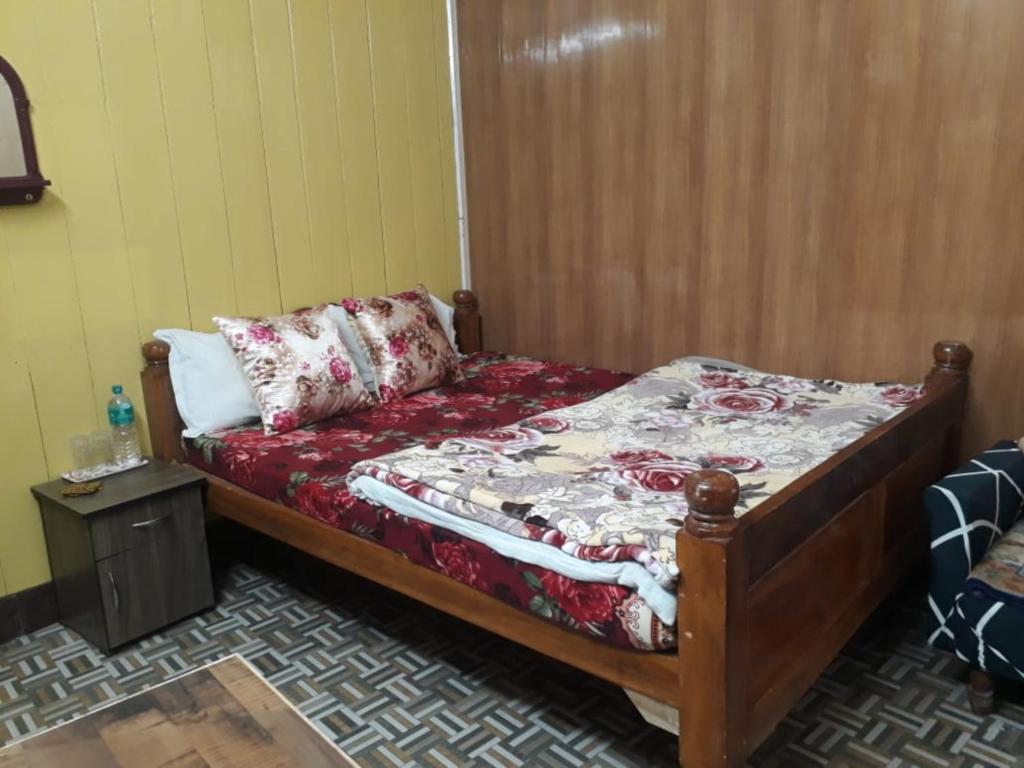 Hotel New Smriya Homestay Inn Darjeeling في دارجيلنغ: غرفة نوم صغيرة مع سرير وطاولة