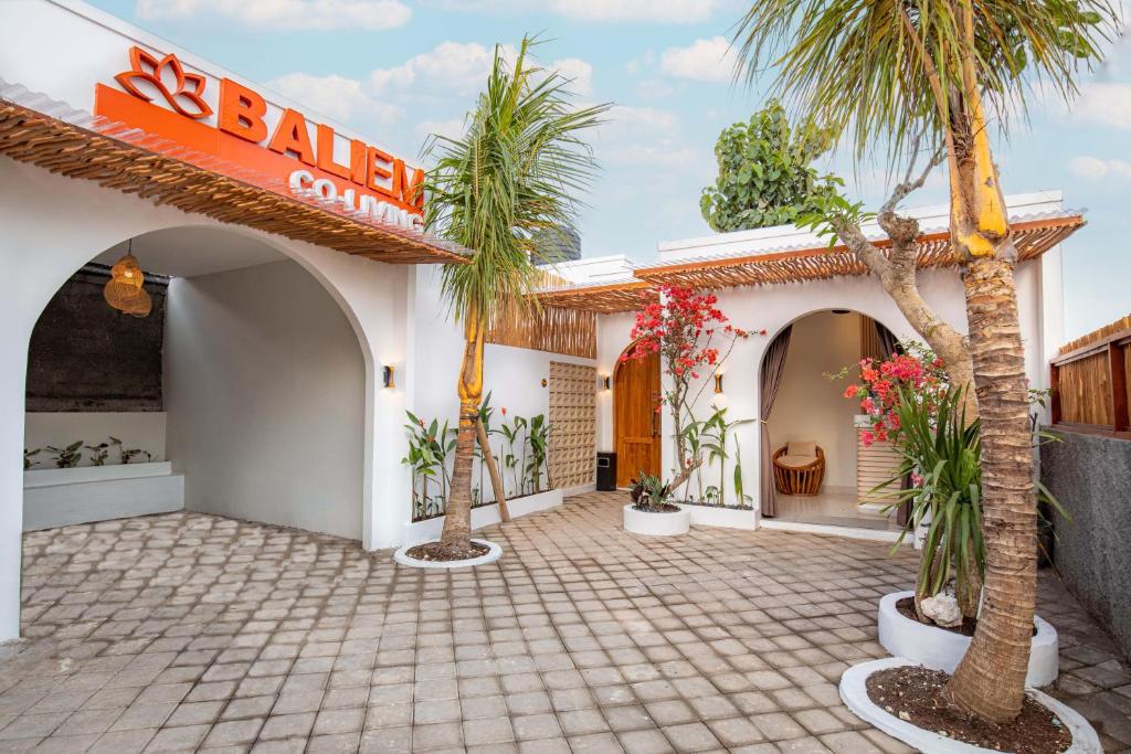 a hotel with palm trees in a courtyard at Baliem CoLiving in Jimbaran