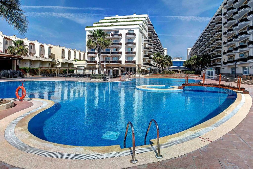 une grande piscine en face d'un bâtiment dans l'établissement Peñiscola Plaza Suites, à Peñíscola