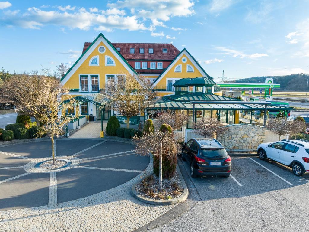 ein großes gelbes Gebäude mit Autos auf einem Parkplatz in der Unterkunft Rasthaus zum Dokl in Gleisdorf