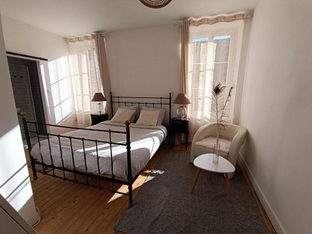 una camera con letto, sedia e finestre di Chambres cosy au coeur du village a Chaumont-en-Vexin