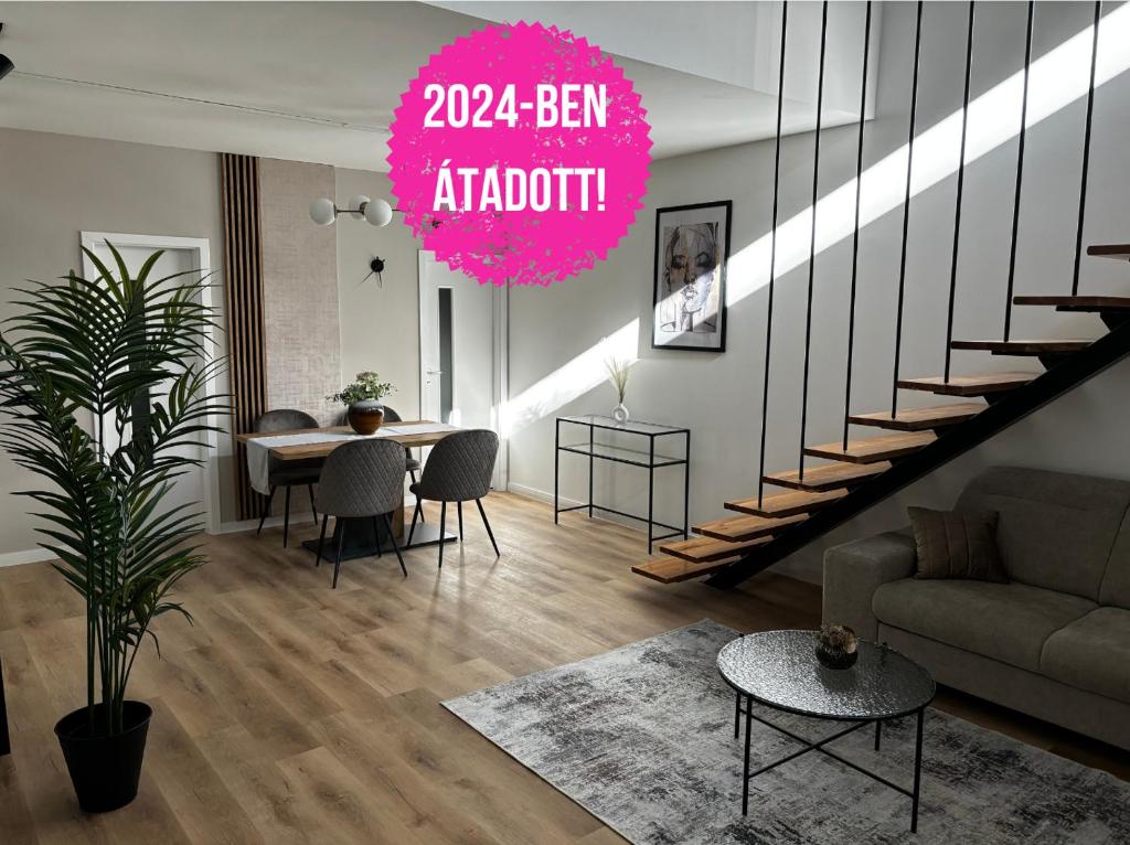 a living room with a table and a spiral staircase at Z8 Prémium Apartman in Kaposvár