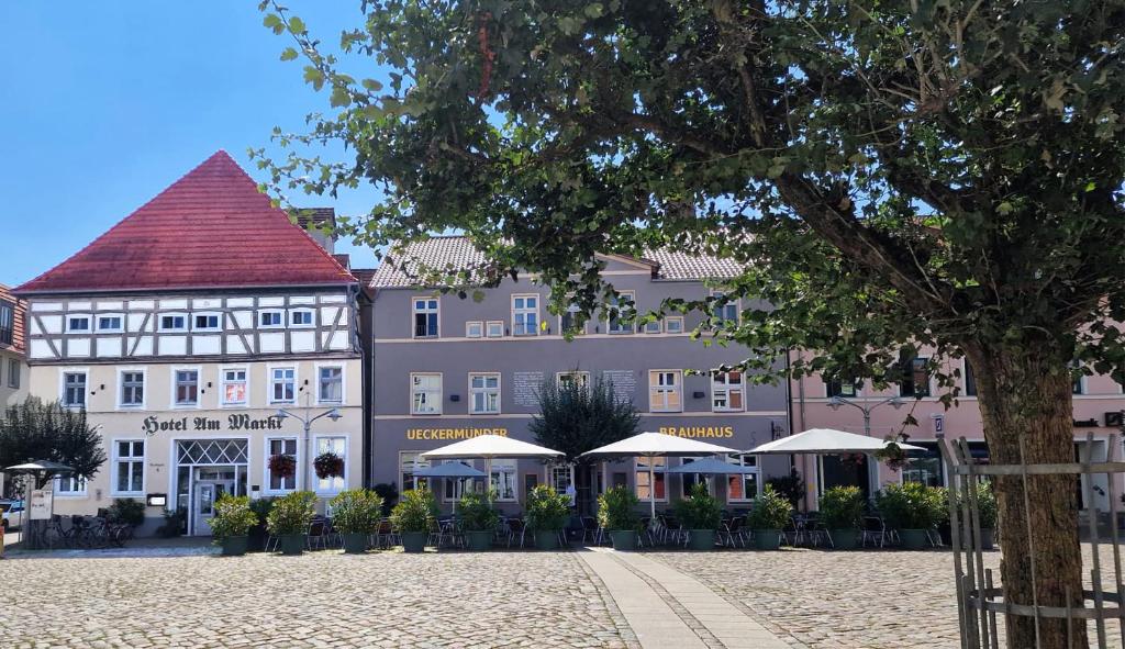 duży budynek ze stołami i parasolami przed nim w obiekcie Hotel Am Markt & Brauhaus Stadtkrug w mieście Ueckermünde