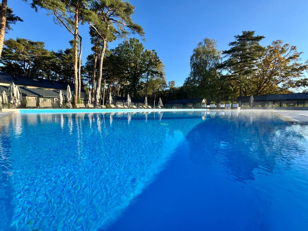 une grande piscine d'eau bleue avec des arbres en arrière-plan dans l'établissement Folga Resort, à Mrzeżyno