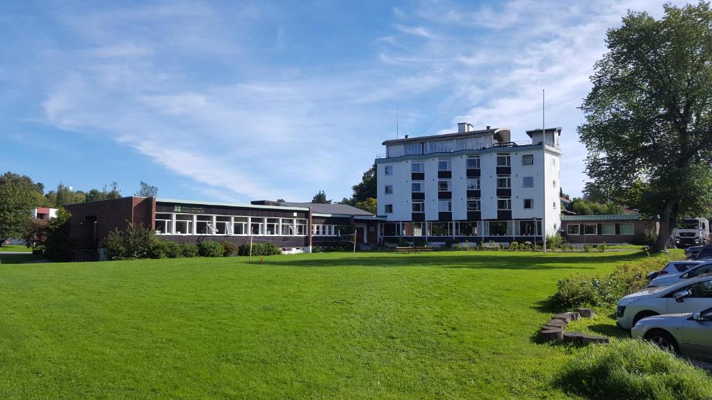 um grande edifício branco com um campo verde em frente em Hostel Oslofjord em Stabekk