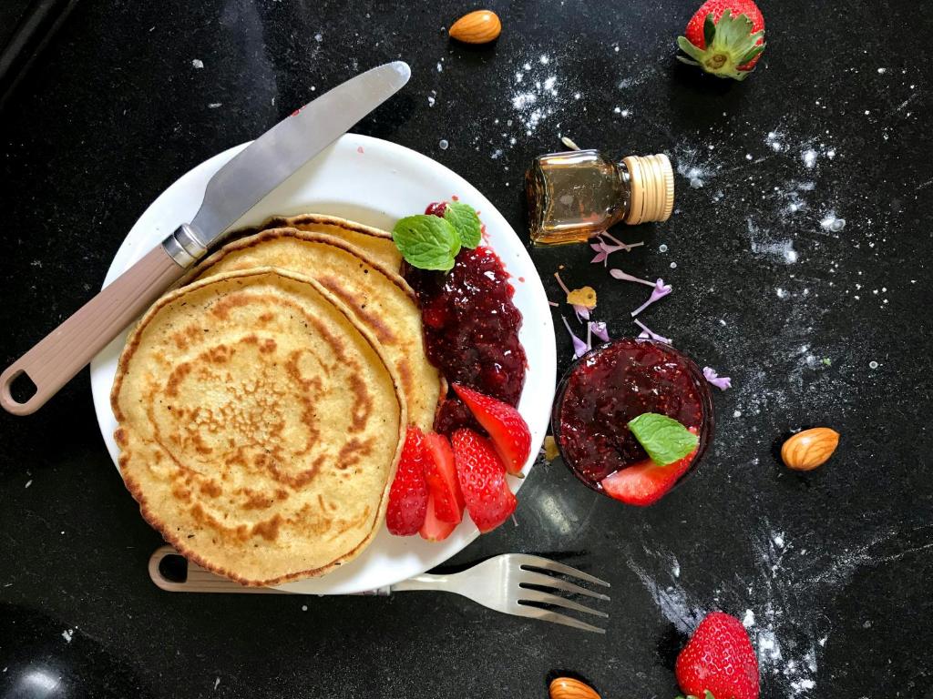 un piatto di pancake e fragole su un tavolo di Hotel Vanson Delite - New Delhi Railway Station a Nuova Delhi