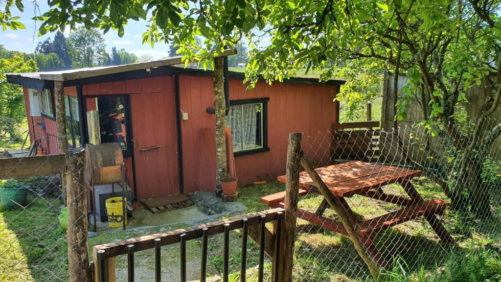 uma pequena casa vermelha com uma mesa de piquenique em frente em Refugio campestre a 7min de Osorno em Osorno