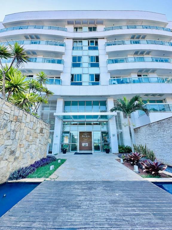 un gran edificio blanco con una entrada delante de él en Mandai Apartamentos, en Cabo Frío