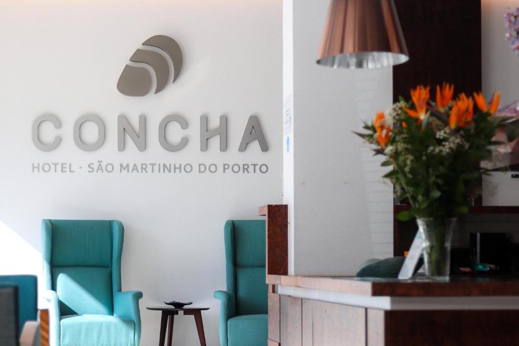 um átrio com cadeiras azuis e um vaso de flores em Hotel Concha em São Martinho do Porto