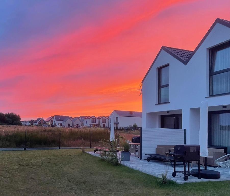 une maison blanche avec un coucher de soleil en arrière-plan dans l'établissement Baltic Apartamenty, à Jastrzębia Góra