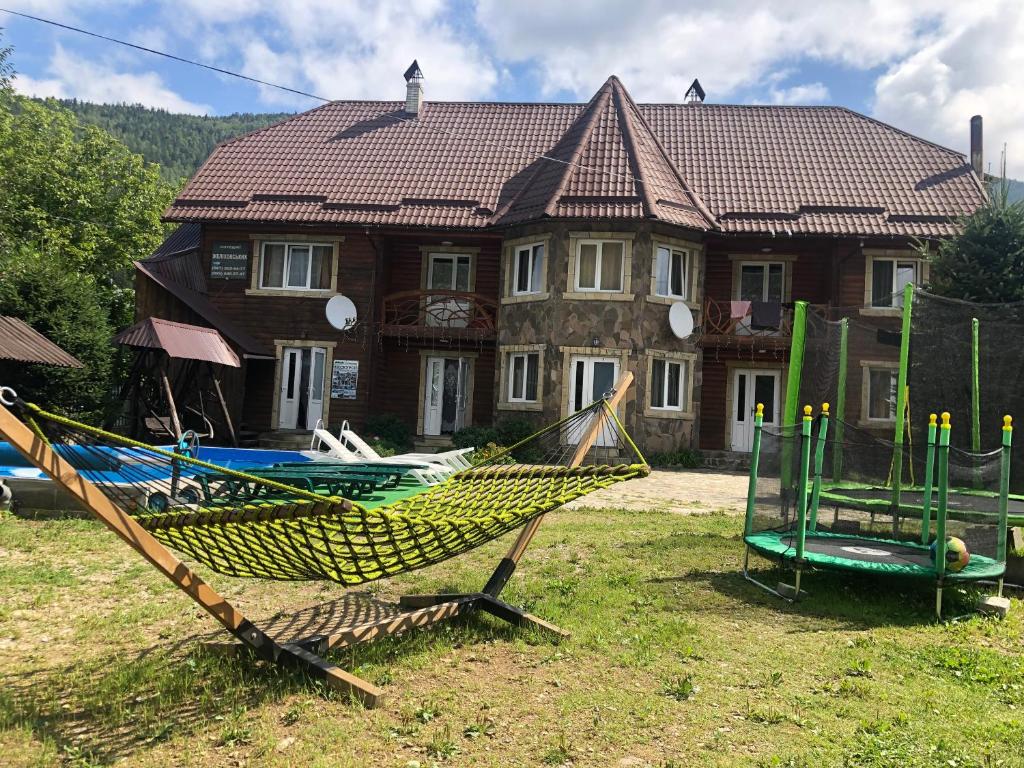 Cottage Zhelikhovskykh في تاتاريف: منزل به أرجوحة أمام المنزل