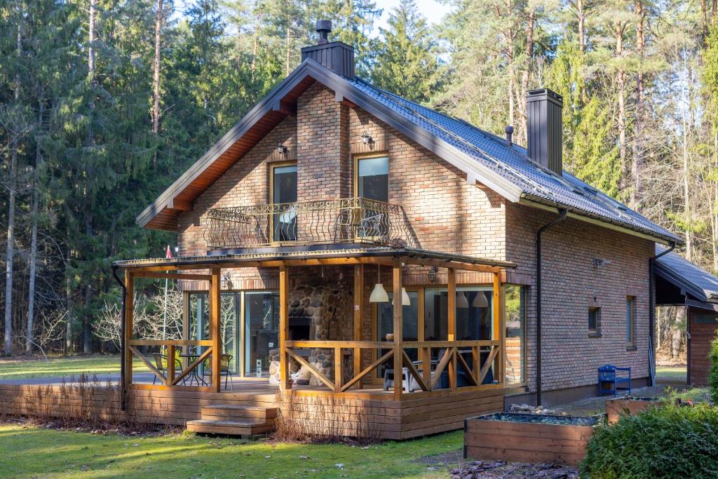 een huis met een veranda rondom en een terras rondom bij Miško Fėja in Birštonas