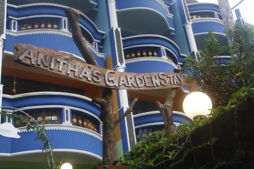 Anitha's Garden Stay في كوفالام: علامة أمام مبنى بالطبول الزرقاء