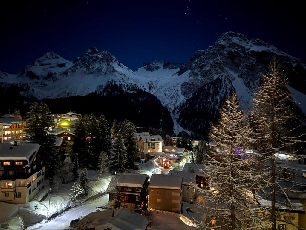 Hotel Seehof-Arosa في أروسا: مدينه في الثلج بالليل مع جبل