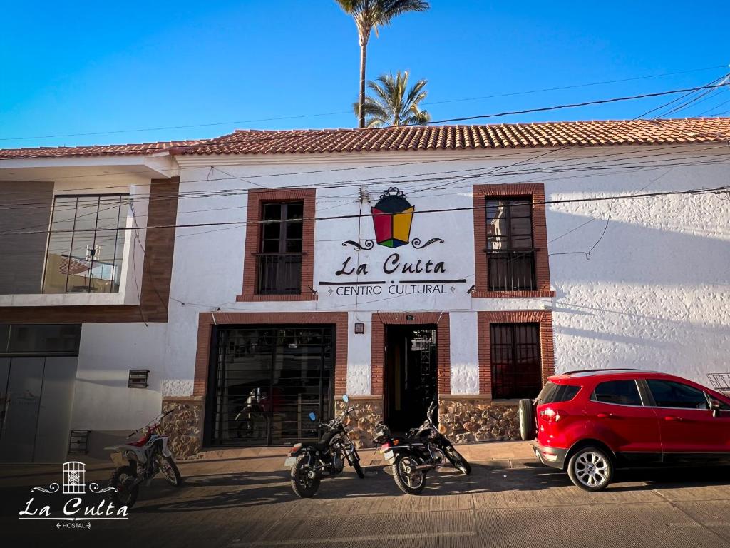 een rode auto geparkeerd voor een restaurant bij La Culta HOSTAL & CASA CULTURAL in Sucre