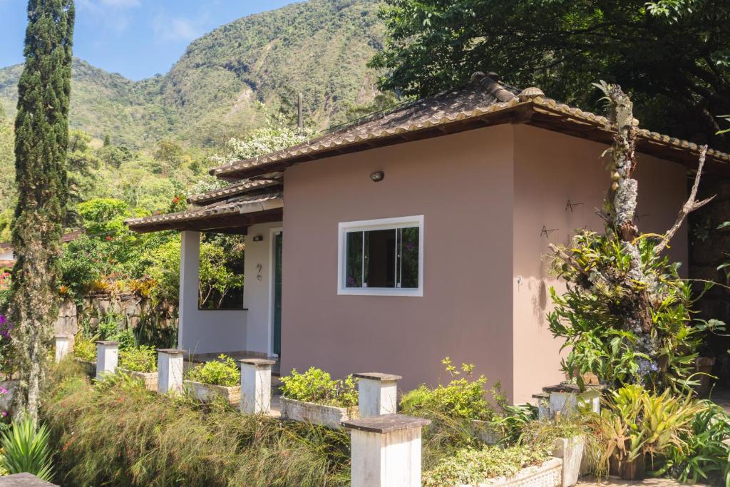 une petite maison avec une montagne en arrière-plan dans l'établissement Chalé Rosa do Vale, à Petrópolis