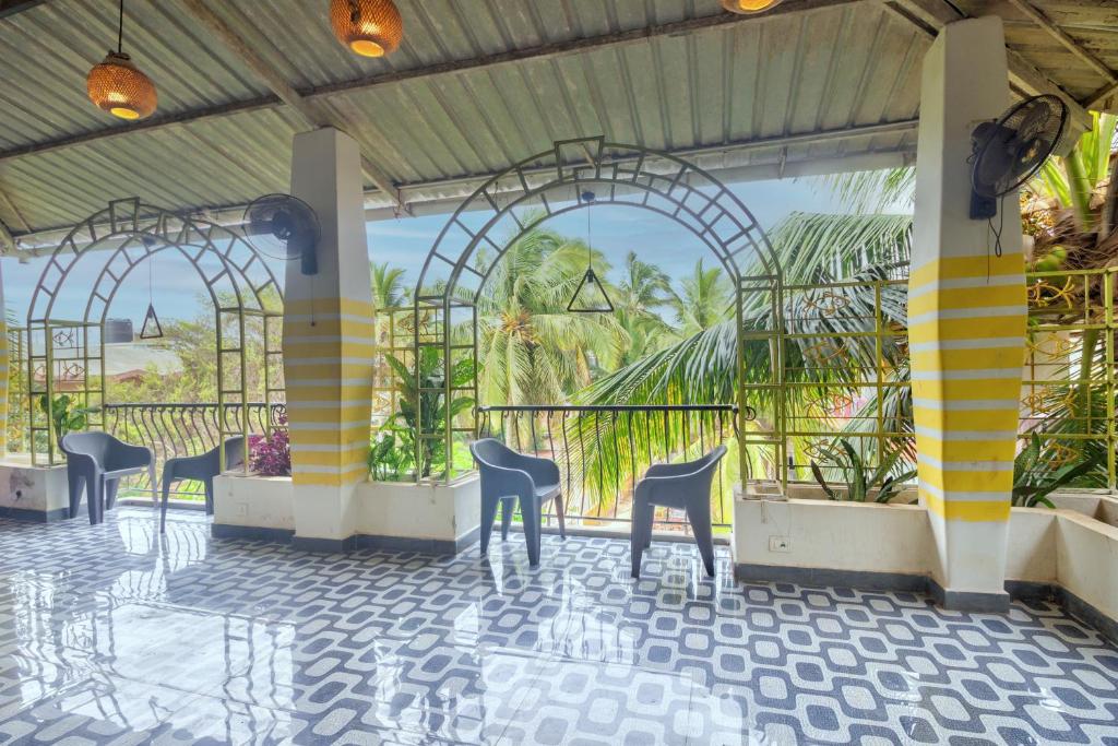 a lobby with chairs and palm trees in the background at Thomson Imperial Boutique G0A in Calangute