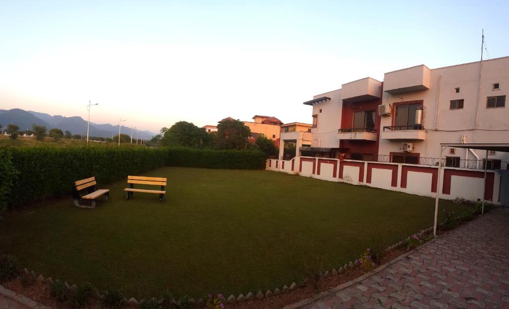 um quintal com um banco e um edifício em Hill Town Guest House Islamabad em Islamabad