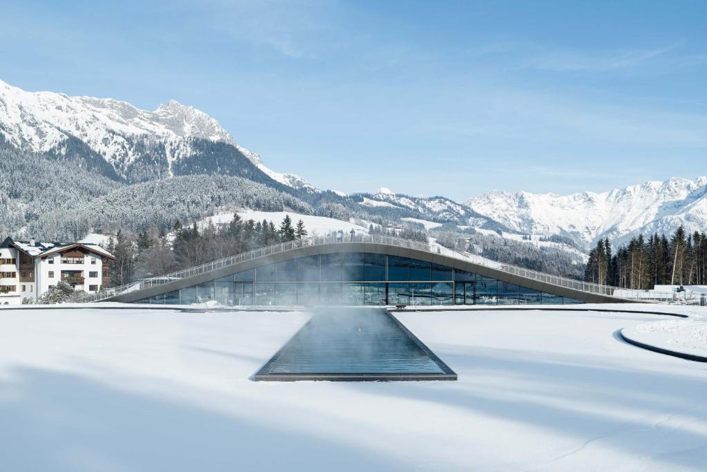 un ponte su un lago ghiacciato con montagne sullo sfondo di Hotel Krallerhof a Leogang