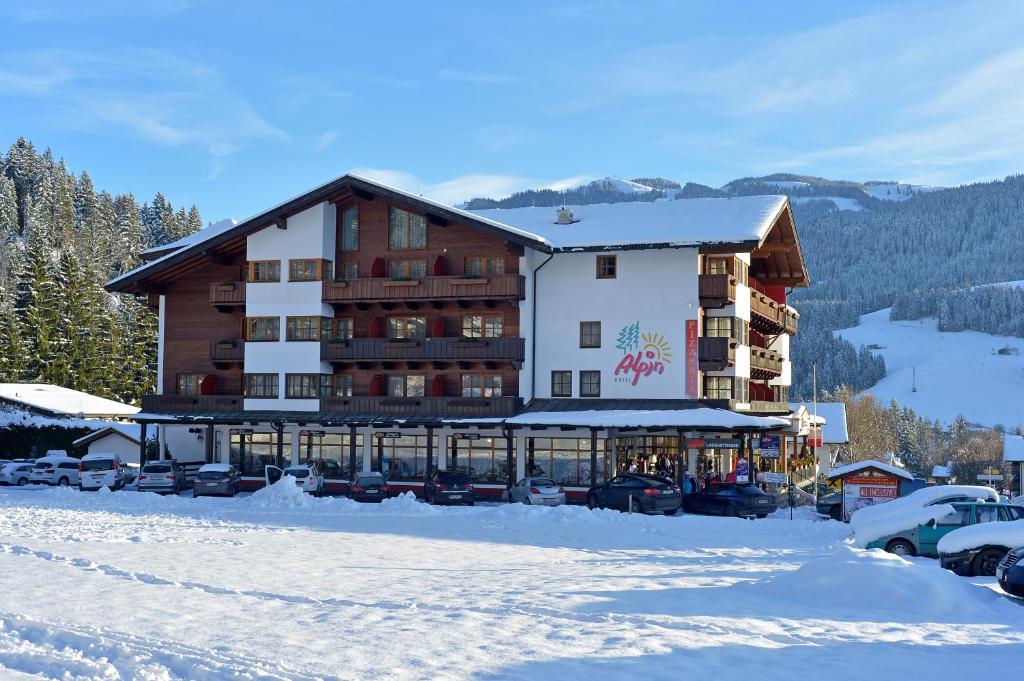 ein großes Gebäude mit Autos im Schnee in der Unterkunft Das Alpin - Hotel Garni Guesthouse in Scheffau am Wilden Kaiser