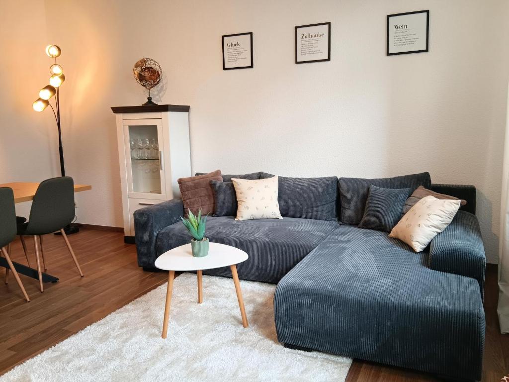 ein Wohnzimmer mit einem blauen Sofa und einem Tisch in der Unterkunft Ferienwohnung Gemütliche Auszeit - Wallbox, nur 50m zum Hauptbahnhof, ruhig, Parterre, zentral, Hunde willkommen, Kinderausstattung vorhanden in Gotha