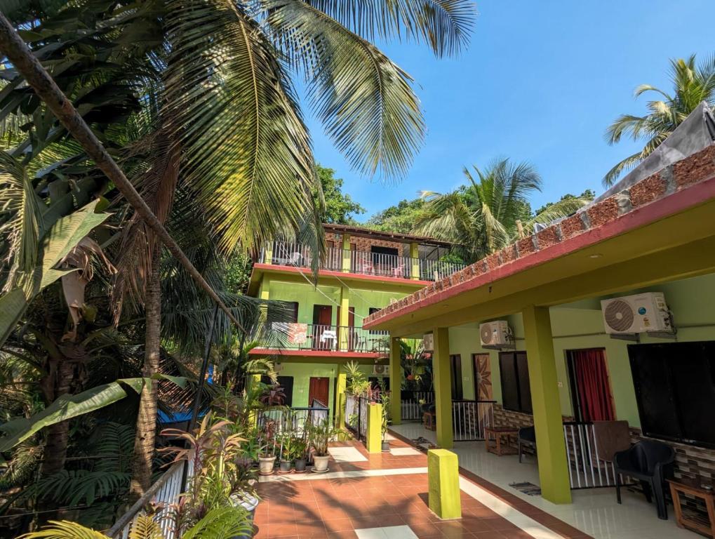 een geel gebouw met palmbomen ervoor bij Luciano Guest House in Arambol