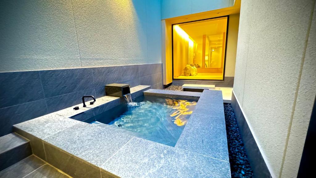 ein Badezimmer mit einer großen Badewanne und einem Koi-Teich in der Unterkunft THE KAKU Exclusive suite & Residence in Nara