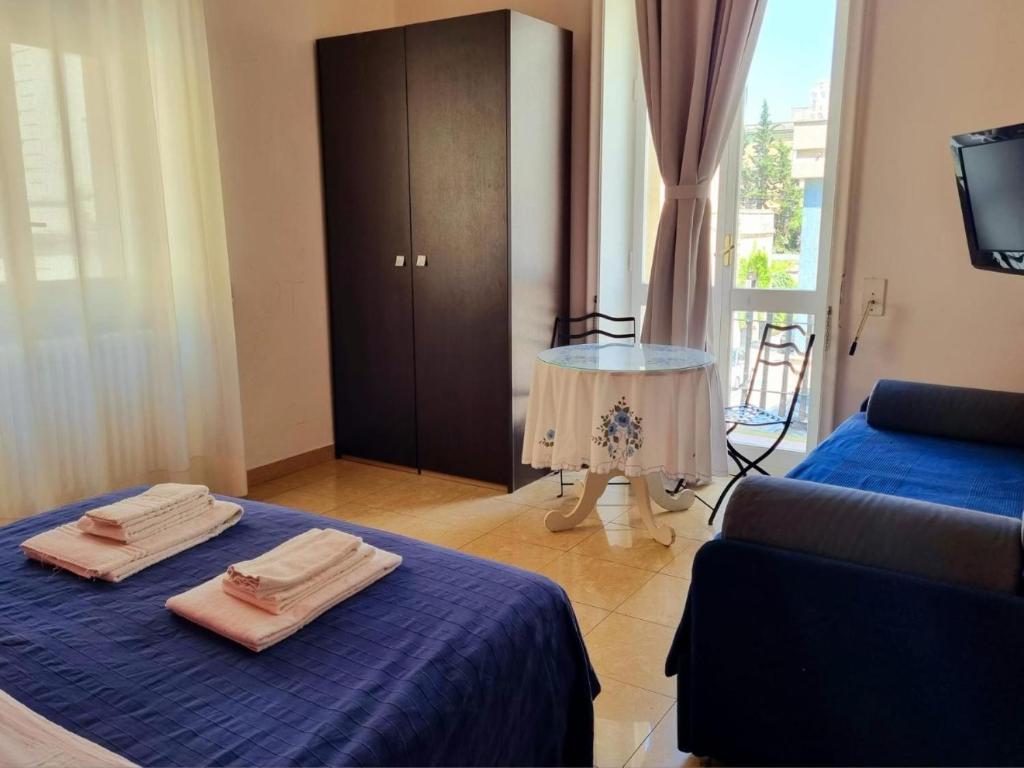 een kamer met 2 bedden, een bank en een tafel bij Harmony Central in Lecce