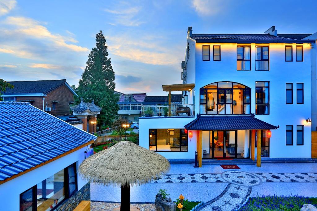 a large white house with a straw umbrella at Shanghai Chuxin Moshe B&B Disney Store in Shanghai