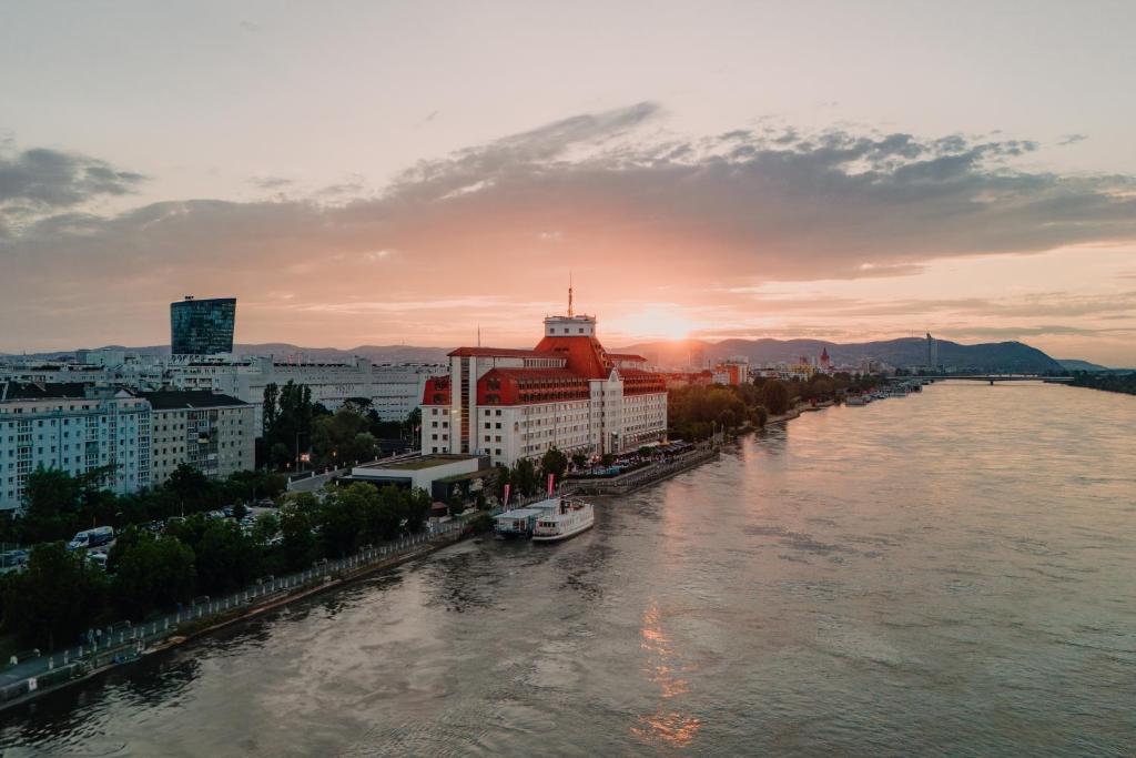 Hilton Vienna Waterfront في فيينا: اطلاله على نهر فيه مباني ومدينه