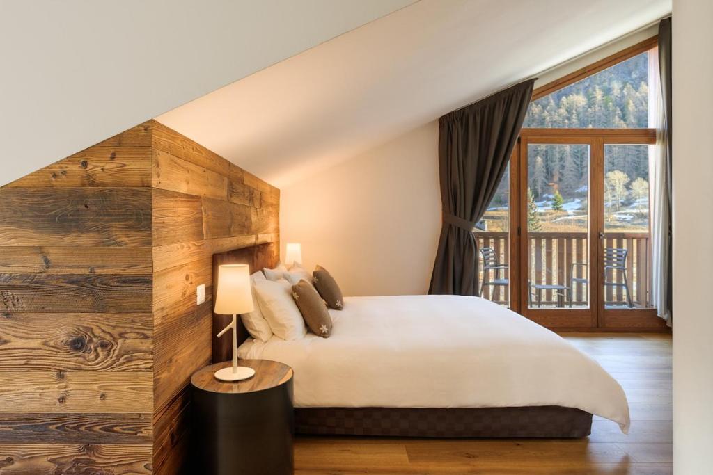 1 dormitorio con cama y ventana grande en Montana Lodge & Spa, by R Collection Hotels, en La Thuile