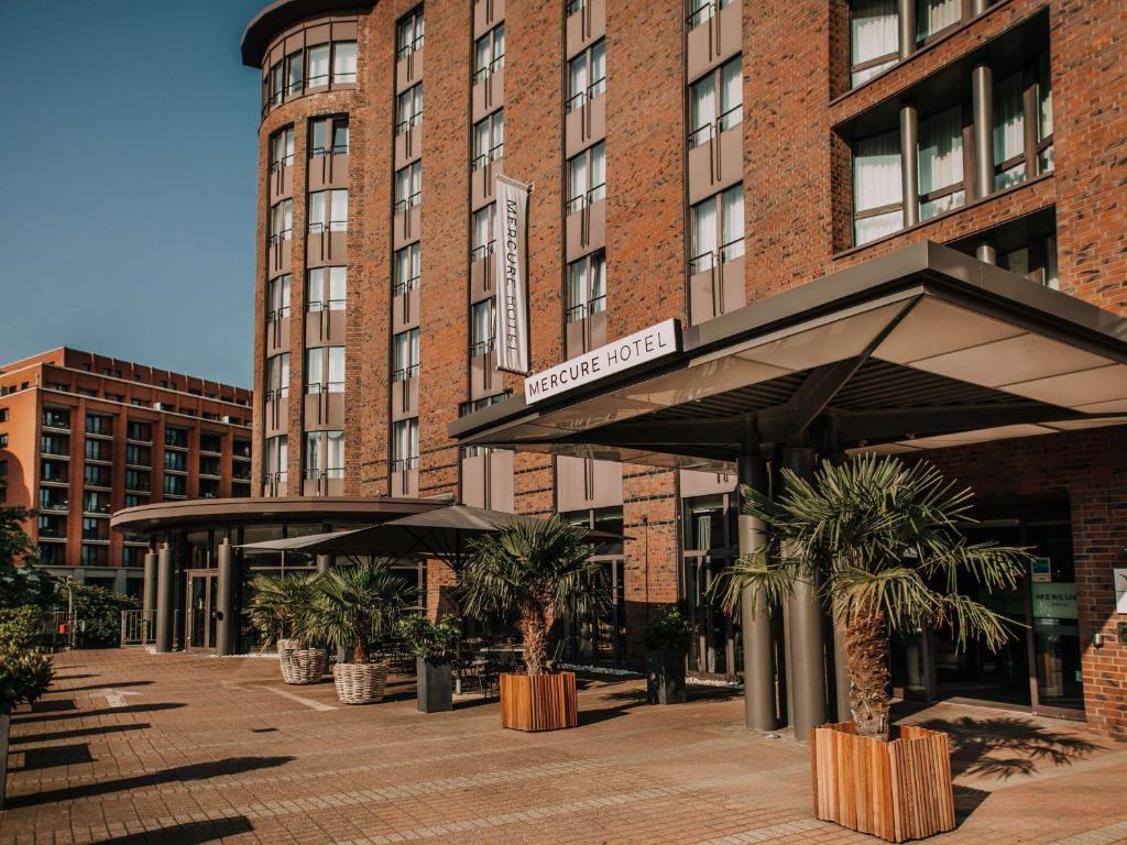 a hotel with palm trees in front of a building at Mercure Hotel Hamburg City in Hamburg