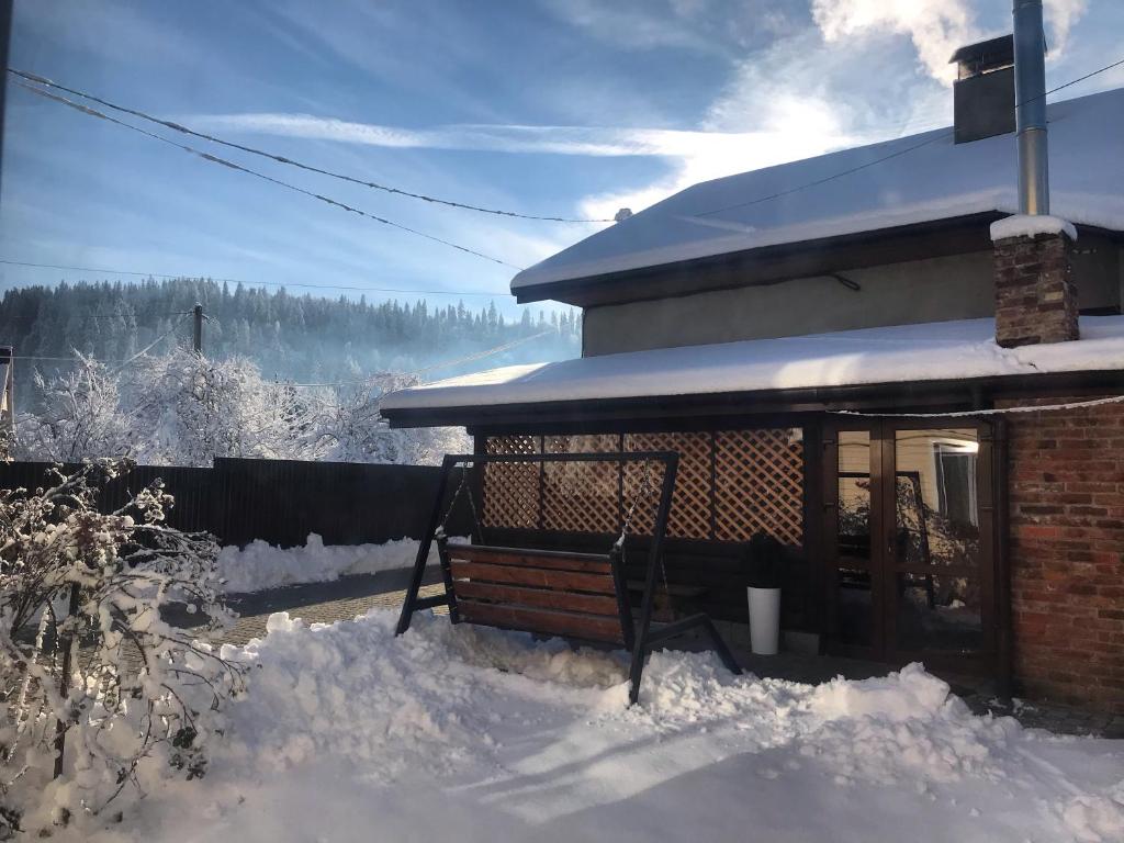 una casa con un banco en la nieve en Артемів двір, en Slavske