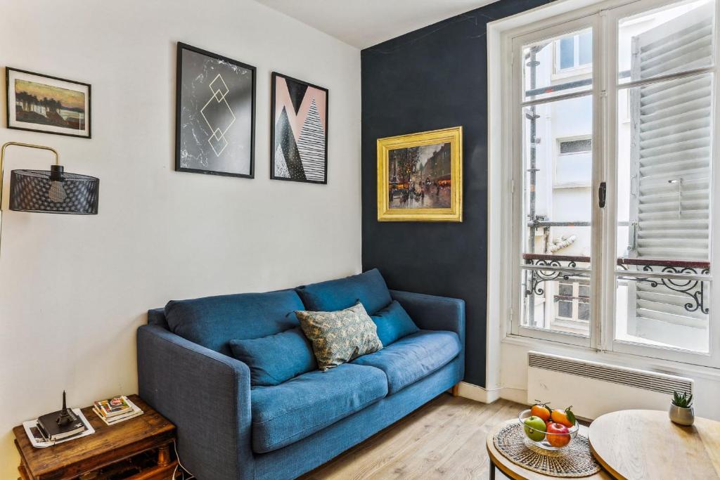 - un canapé bleu dans le salon doté d'une fenêtre dans l'établissement BnBNova - 1BR - Invalides & Tour Eiffel, à Paris