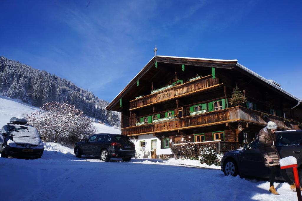 un grand bâtiment en bois avec des voitures garées dans la neige dans l'établissement MyApart 1709, à Jochberg